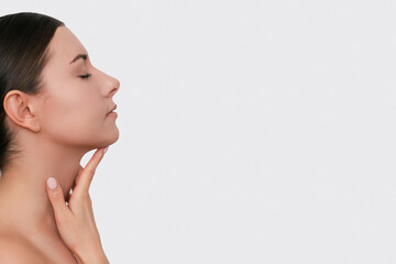 Profile of a young Caucasian dark-haired woman gently touching her neck. Isolated on a white...