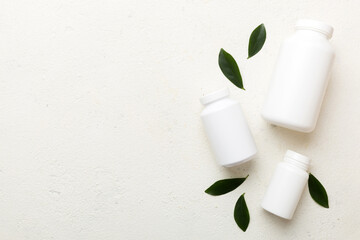 supplement pills with medicine bottle health care and medical top view. Vitamin tablets. Top view mockup bottle for pills and vitamins with green leaves, natural organic bio supplement, copy space