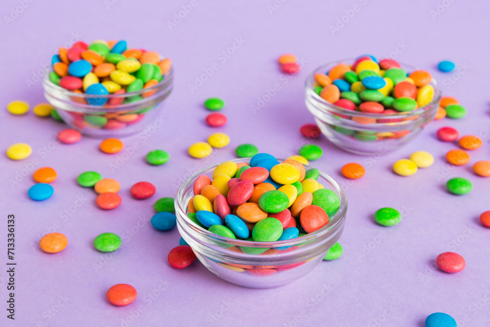 Poster Multicolored candies in a bowl on a colored background. birthday and holiday concept. Top view with copy space