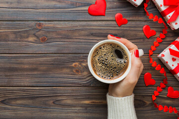 Flat lay of heart shaped cup of black coffee in the hands of women on colored background with copy space top view. Valentine day and holiday concept