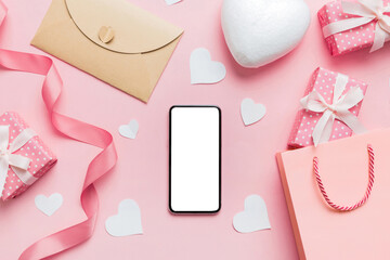 Obraz na płótnie Canvas mobile phone with blank screen on colored background with hearts, valentine day concept top view flat lay