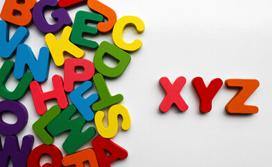 English Alphabet On A White Background. alphabets on a wooden surface. xyz - letters. scattered mixed colorful wooden letters of the English alphabet on backdrop, copy space,  background composition