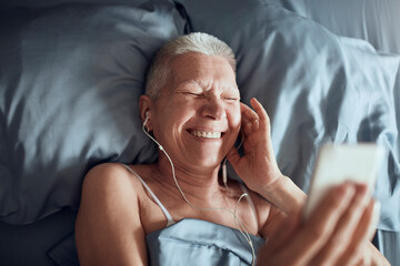 Smiling senior woman listening to music in bed