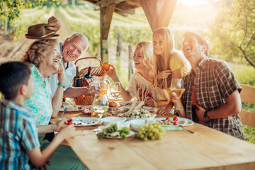 Happy family enjoying meal together in vineyard - Powered by Adobe