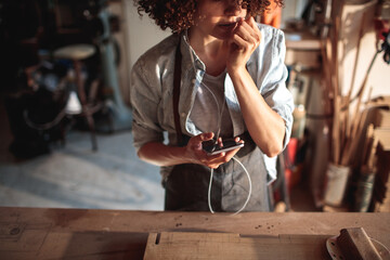 Craftswoman listening to music in woodshop