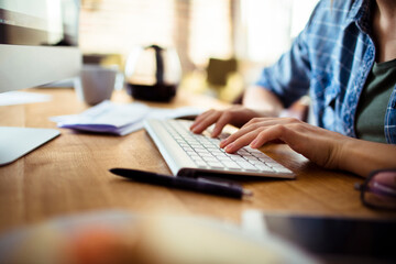 Freelancer working on computer with breakfast sandwich on desk