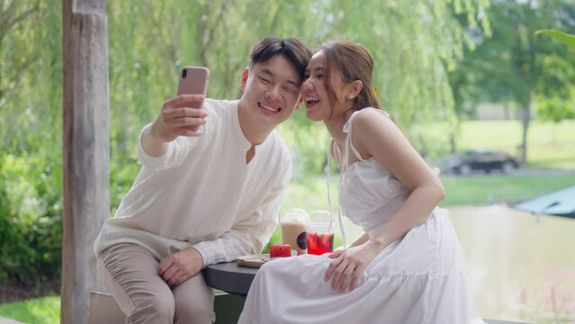 Asia people young adult man woman relax smile looking at camera take photo falling in love flirt at outdoor cafe enjoy fun date day. Joy happy asian lovers wife husband just married sweet newlywed.