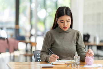 Sharing good business news. Attractive young businesswoman talking on the mobile phone and smiling while sitting at her working place in office and looking at laptop PC.