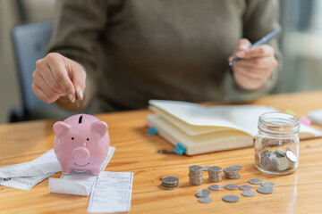  hand of businesswoman, putting money coin into piggy bank for saving money. saving money and...