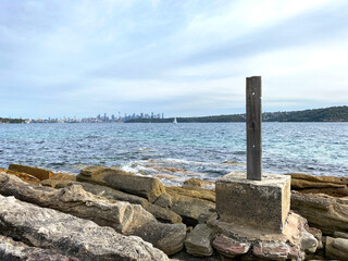 Old abandoned pier in the sea. Wooden pole that stands alone on a rocky bay. Australian city...