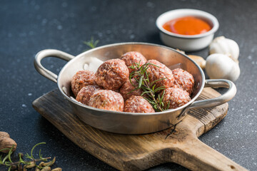 Raw meatballs in pan on the wooden cutting board