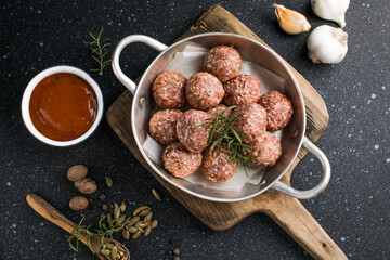 Raw meatballs in pan on the wooden cutting board
