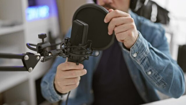 Focused man with headphones adjusting microphone in modern recording studio