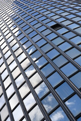 Detail of the glass window grid on a building with reflections of clouds and sky - architectural abstraction