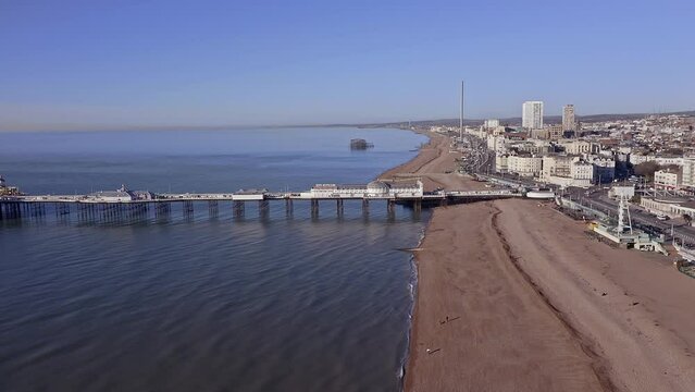 Aerial footage revealing Brighton Beach towards the Victorian Palace Pier, a popular seaside resort in East Sussex England.