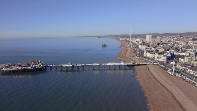 Aerial footage along Brighton Beach towards the Victorian Palace Pier, a popular seaside resort in East Sussex England.