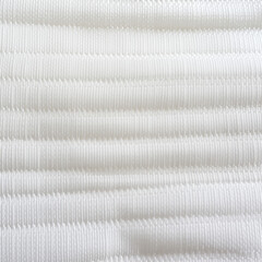 Diagonal white cable knit texture with shadow and light interplay on soft fabric