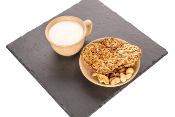Several Thaler cookies with nuts on a slate stone with a cup of sour cream, close-up, isolated on a white background.