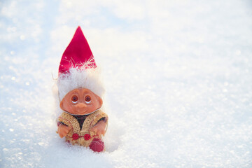 Cute little funny dwarf in the snow in the landscape in winter. A wizard on a snowy background. Christmas and New Year