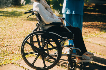 Nursing staff talking to an elderly person sitting in a wheelchair.