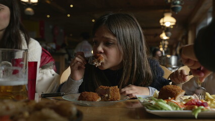 Cozy Dining Delight - Little Girl Enjoying Cordon Bleu Chicken at Family Mealtime in Wooden Interior Diner, people eating food at restaurant