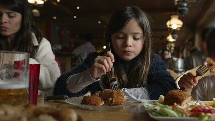 Cozy Dining Delight - Little Girl Enjoying Cordon Bleu Chicken at Family Mealtime in Wooden Interior Diner, people eating food at restaurant