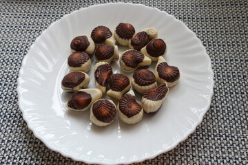A plate with chocolates on the table. Candies in the shape of a shell.