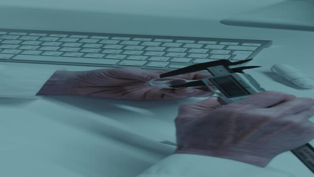 Vertical shot of Caucasian female laboratory worker measuring plastic prototype of future arm prosthetic with digital caliperVertical shot of Caucasian female laboratory worker measuring plastic proto