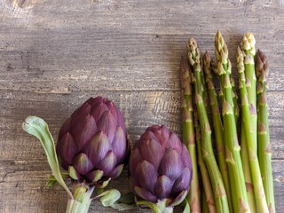 Purple artichokes and asparagus lie on the table
