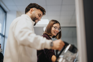 Young coworkers in a modern kitchen enjoying their morning coffee and tea. They are having a...
