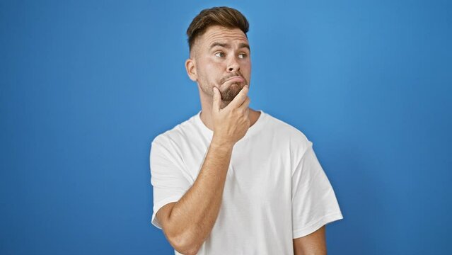 Handsome young adult hispanic man with beard touches chin thinking then has idea against blue background