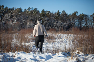 Młoda kobieta spacerująca zimą po górskim szlaku, ośnieżona łąka - obrazy, fototapety, plakaty