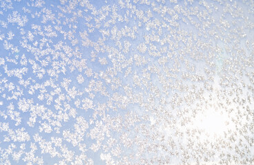 Abstract winter background. Frost on a frozen window against the blue sky.