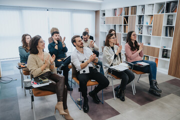 A group of attentive colleagues clapping after a presentation at a corporate training session. They...