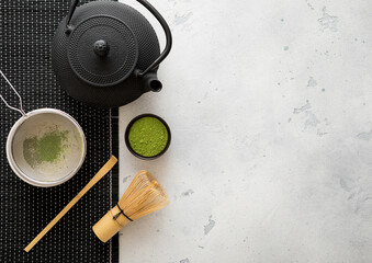 Japanese iron kettle with matcha green tea powder with whisk and spoon and bowl with sifter on...