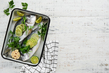 Raw fresh. Fresh raw dorado with lemon, lime, parsley and salt on old wooden white background ready...