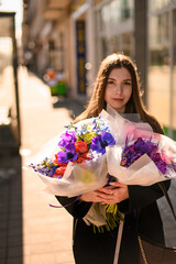 Fototapeta premium Smiling woman holding bouquets of different flowers in light wrappers