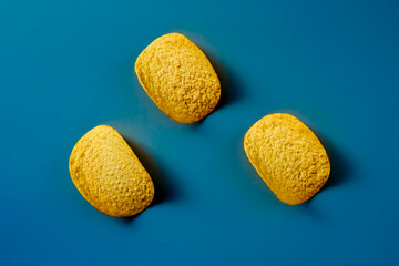 Golden and crusty potato chips on blue background. Minimalistic food photo. 