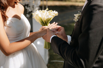 Wedding ceremony of exchange of engagement rings. The bride and groom put on wedding rings and take...