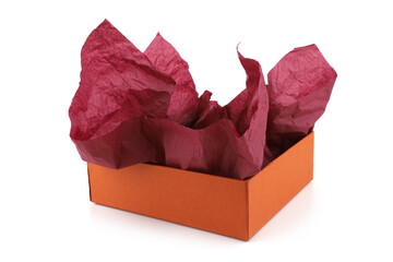 Orange carton box with burgundy wrapping paper isolated on white background. Empty open gift packing box and crumpled parchment paper for gift.