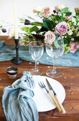 Bouquets of pink flowers on a table set for dinner with candles