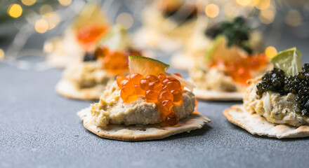 Holiday canapes with red and black caviar, on crackers festive silver Christmas decoration, copy space, selected focus, narrow depth of field