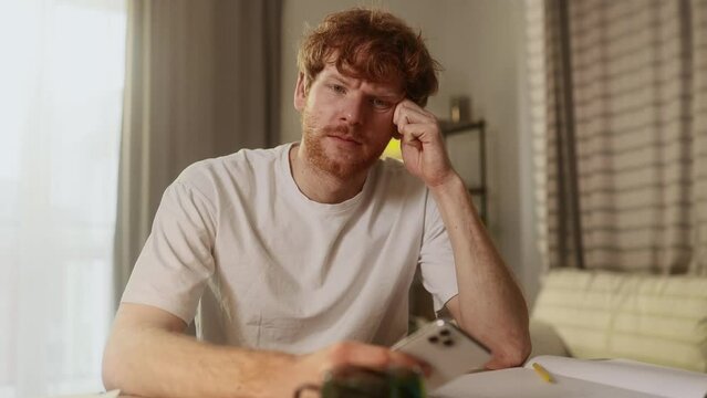 Attractive young red haired man at home workplace get notification and feeling upset reading bad negative news message at smartphone indoors Disappointment Fail Unemployment