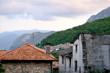 Fototapeta na wymiar Tile roofs of old buildings, medieval semi-ruined facades against backdrop of mountains, historical architecture of Mediterranean cities