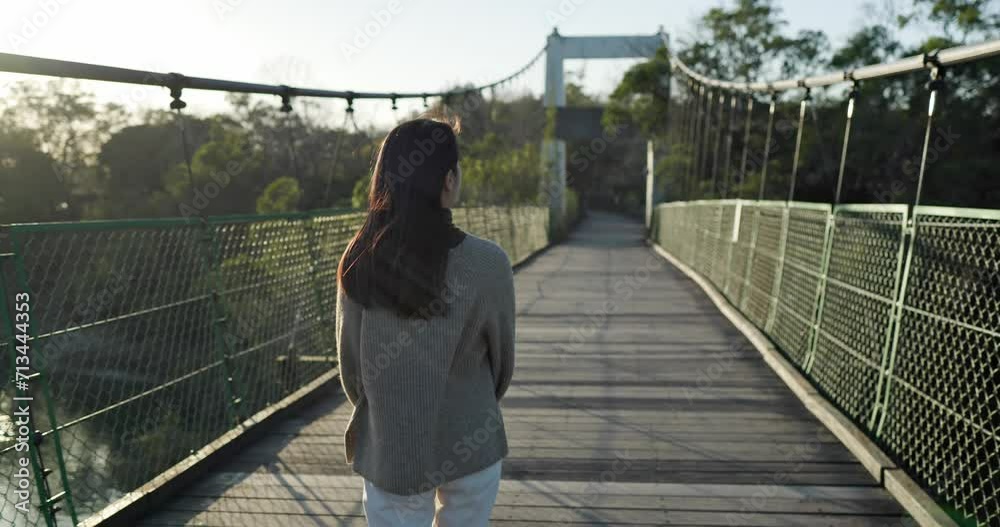 Poster woman walk along the suspension bridge in countryside