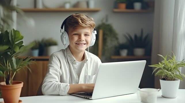 Smiling boy sitting at desk with laptop. Student study at home and learning online