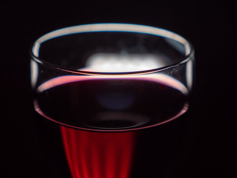 An artistic image of a red wine glass on a black background.