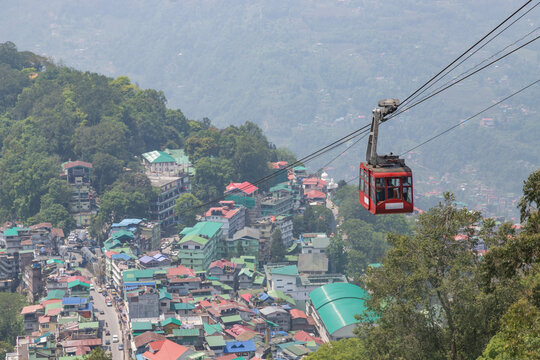 Tourists enjoy a ropeway cable car gondola ride over gangtok city during sunset. Amazing aerial cityscape of sikkim. North east India tourism