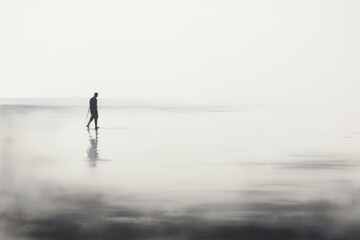 Fototapeta na wymiar a black and white photo of a person standing on the beach with a surfboard in the foggy water.