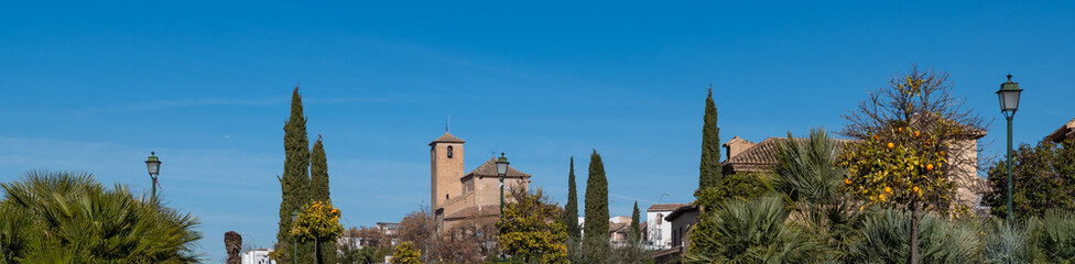 Fototapeta na wymiar Panoramic view of the upper Albaicin (Granada, Spain) with the church of San Cristóbal between cypresses on a sunny winter morning